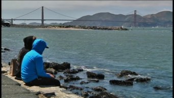 People dangle feet in Bay at Crissy Field