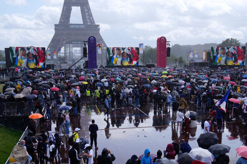 People watch the closing ceremony of the Tokyo 2020 Olympic Games on giant screens in the Olympics fan zone at Trocadero Gardens in front of the Eiffel Tower in Paris, Sunday, Aug. 8, 2021. A giant flag will be unfurled on the Eiffel Tower in Paris Sunday as part of the handover ceremony of Tokyo 2020 to Paris 2024, as Paris will be the next Summer Games host in 2024. The passing of the hosting baton will be split between the Olympic Stadium in Tokyo and a public party and concert in Paris.