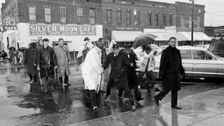 In this March 1, 1965 file photo Dr. Martin Luther King Jr. hops over a puddle as it rains in Selma, Ala. King led hundreds of African Americans to the court house in a voter registration drive.