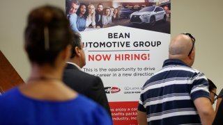 People stand in line to inquire about jobs available at the Bean Automotive Group during a job fair in Miami.
