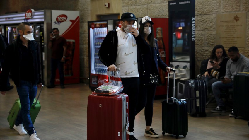 Passengers wearing protective masks arrive in Ben Gurion Airport near Tel Aviv, Israel, Thursday, Feb. 27, 2020. Israel on Wednesday advised its citizens to reconsider all foreign travel amid the global spread of the new coronavirus that was first reported in China. (AP Photo/Ariel Schalit)