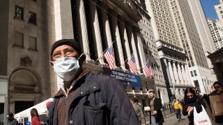 In this March 6, 2020, file photo, a man wears a mask as he passes the New York Stock Exchange in New York City.