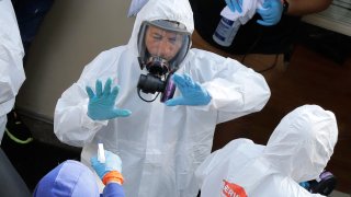 Servpro cleaning workers are sprayed as they exit the Life Care Center in Kirkland, Wash., Thursday, March 12, 2020, at the end of a day spent cleaning inside the facility near Seattle. The nursing home is at the center of the outbreak of the new coronavirus in Washington state.