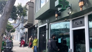 Customers maintain social distance while waiting to enter The Green Cross cannabis dispensary in San Francisco, March 18, 2020. As about 7 million people in the San Francisco Bay Area are under shelter-in-place orders, only allowed to leave their homes for crucial needs in an attempt to slow virus spread, marijuana stores remain open and are being considered "essential services."