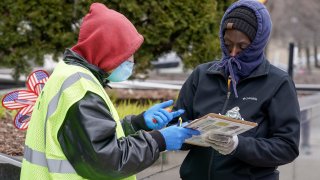 A worker helps voter outside the Frank P. Zeidler Municipal Building Monday March 30, 2020, in Milwaukee.