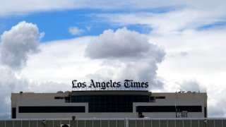 The new Los Angeles Times building is seen behind a fence behind the Los Angeles International Airport, Friday, April 10, 2020. California newspapers are asking the state to help rescue their industry, as the economic crisis from the coronavirus slashes print advertising revenues, causing layoffs in an already battered industry, even as reporters are deemed essential workers during the pandemic. (AP Photo/Richard Vogel)