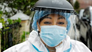 In this Thursday, April 30, 2020, photo, Linda Silva, a nurse's assistant, poses for a portrait in the Queens borough of New York. Silva, who tested positive for COVID-19, returned to work after recovering. It’s been more than a month since she has hugged her two sons or her husband.