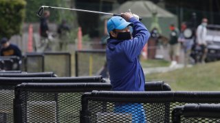 Cam Kim wears a face mask while hitting from the driving range at Presidio Golf Course during the coronavirus outbreak in San Francisco, Sunday, May 10, 2020.