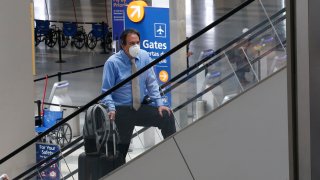 In this May 11, 2020, file photo, a traveler wears a face mask as he goes to the boarding gates at Sacramento International Airport in Sacramento, Calif.