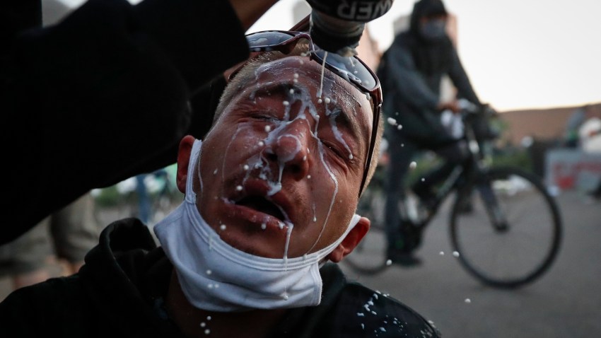A protester is assisted with a solution to help neutralize the effects of tear gas fired by police outside the Minneapolis 5th Police Precinct, Saturday, May 30, 2020, in Minneapolis. Protests continued following the death of George Floyd, who died after being restrained by Minneapolis police officers on Memorial Day.