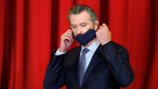 California Gov. Gavin Newsom takes off his face mask before a news conference, June 1, 2020, in Sacramento, California. A Chinese company paid by California to manufacturer hundreds of millions of protective masks missed a Sunday deadline for federal certification, marking the second times its shipments to the state will be delayed.
