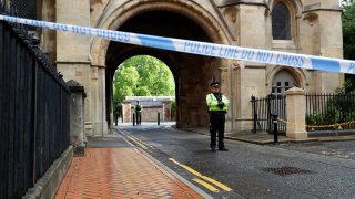 Police stand guard at the Abbey gateway of Forbury Gardens park in Reading town centre following Saturday's stabbing attack in the gardens, Sunday June 21, 2020