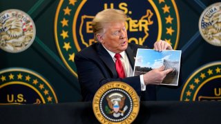 President Donald Trump holds an image of the U.S. border wall