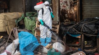 In this March 22, 2020, file photo, a municipal worker sanitizes the street of Dakar's popular Medina neighborhood after a bulldozer demolished informal shops in an effort to stop the spread of the coronavirus.