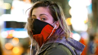 Brooklyn resident and waitress Casey Stewart peers out from a ski mask she adapted to protect herself from coronavirus after riding the subway to Times Square, March 12, 2020, in New York. She is also wearing a protective mask beneath the ski mask.