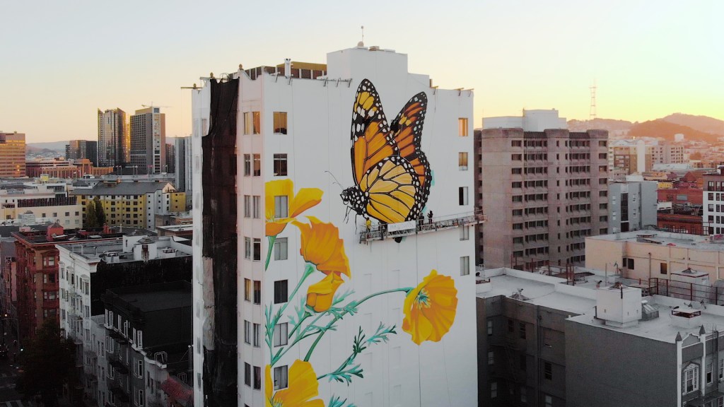large orange butterfly painted on a tall building
