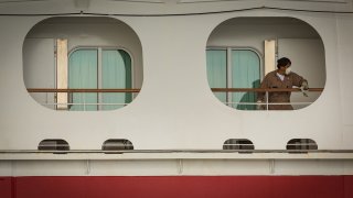 A worker wearing a protective mask cleans a handrail aboard the Carnival Corp. Miracle cruise ship anchored at the Port of Long Beach in Long Beach, California, April 13, 2020.