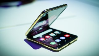 A folding smartphone with gold edges on a white tabletop