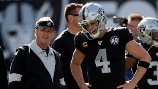 Jon Gruden of the Oakland Raiders talks to quarterback Derek Carr.