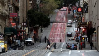 Few pedestrians walk along Powell Street in San Francisco during commute hours.