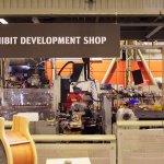 "exhibit development shop" sign above a messy workshop full of equipment