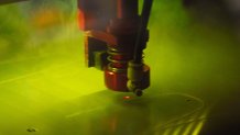 a laser cutter etches a pattern that looks like fingers into a sheet of plastic