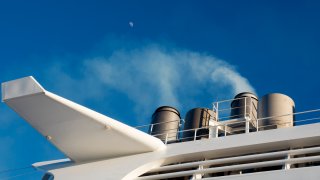 Tauranga, New Zealand – 1 March 2019 Here we see a cruise liner’s funnel smoking whilst moored in Taurange Harbour in the Bay of Plenty, New Zealand. Please note this shot was taken from a public – access pier. Emissions from transport and shipping are major contributors to the greenhouse effect and, consequently, global warming.