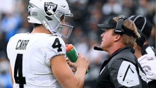CARSON, CALIFORNIA – DECEMBER 22: Head coach Jon Gruden of the Oakland Raiders speaks to Derek Carr #4 during a 24-17 win over the Los Angeles Chargers at Dignity Health Sports Park on December 22, 2019 in Carson, California. (Photo by Harry How/Getty Images)