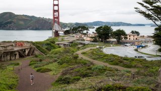 A jogger runs past an empty parking lot and the Golden Gate Bridge in the Golden Gate National Recreation Area in San Francisco, California, U.S., on Wednesday, March 18, 2020. Six of the biggest counties in the San Francisco Bay Area ordered people to stay home except for essential needs, marking one of the nation’s strongest local efforts yet to stem the spread of the coronavirus. Photographer: David Paul Morris/Bloomberg via Getty Images