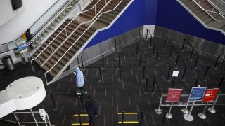 Passengers wearing protective masks enter a Transportation Security Administration (TSA) checkpoint at Los Angeles International Airport (LAX) in Los Angeles on April 9, 2020.