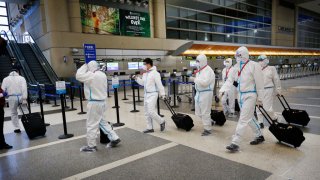 In this May 11, 2020, file photo, the flight crew for a Hainan Airlines flight walks through the Tom Bradley International Terminal, Los Angeles International Airport (LAX), which is now requiring travelers to wear face coverings to help keep fellow passengers and crew safe.