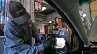 Mike Buckley washes a side mirror as he and his crew complete an oil change while passengers stay in their cars at Grease Monkey on March 23, 2020, in Boulder, Colorado.