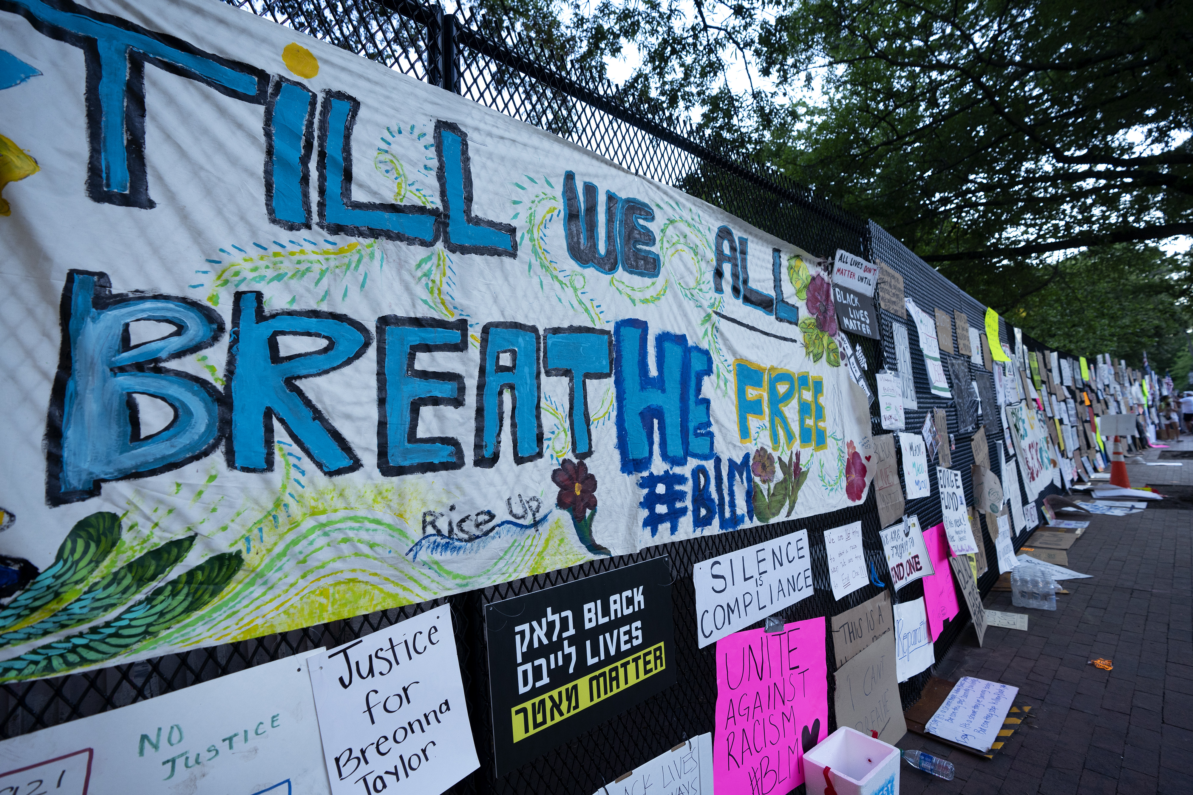 Signs left by demonstrators are taped to the perimeter fencing outside the White House in Washington, D.C., U.S., on Sunday, June 7, 2020.