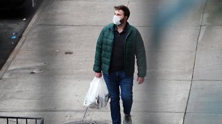 A man wears a protective mask while carrying a shopping bag during the coronavirus pandemic on April 18, 2020 in New York City.