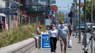 People wearing protective masks walk on Jefferson Street on Fisherman’s Wharf in San Francisco, California, U.S., on Monday, June 22, 2020. California’s new cases rose by a record and Florida infections jumped more than the weekly average, more signs of a possible resurgence of coronavirus in U.S. Sun Belt states. Photographer: David Paul Morris/Bloomberg via Getty Images