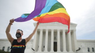 In this June 15, 2020, file photo, Joseph Fons, holding a Pride Flag, stands in front of the U.S. Supreme Court building after the court ruled that LGBTQ people can not be disciplined or fired based on their sexual orientation in Washington, DC.