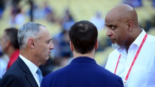 Major League Baseball Commissioner Rob Manfred Jr. talks with Executive Director of the Major League Baseball Players Association Tony Clark during batting practice prior to Game 2 of the 2017 World Series between the Houston Astros and the Los Angeles Dodgers at Dodger Stadium on Wednesday, October 25, 2017 in Los Angeles.