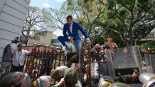 National Assembly President Juan Guaido, Venezuela's opposition leader, tries to climb the fence to enter the compound of the Assembly, after he and other opposition lawmakers were blocked by police from entering a session to elect new Assembly leadership in Caracas, Venezuela, Sunday, Jan. 5, 2020. With Guaido stuck outside, a rival slate headed by lawmaker Luis Parra swore themselves in as leaders of the single-chamber legislature. (AP Photo/Matias Delacroix)