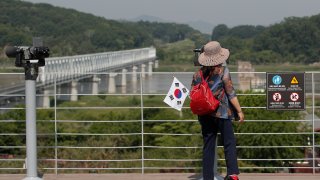 A visitor carrying a South Korean flag uses binoculars to view the northern side at the Imjingak Pavilion in Paju, South Korea, Tuesday, June 9, 2020.