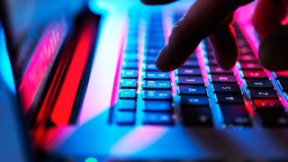 Man typing at his laptop computer at night