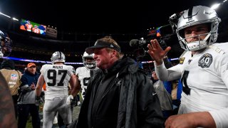 Head coach Jon Gruden of the Oakland Raiders walks onto the field with Derek Carr