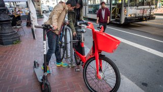 People unlock a bike in San Francisco.
