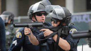 A San Jose Police officer prepares to fire a rubber bullet at a protester.