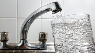 glass of water is filled at a kitchen tap