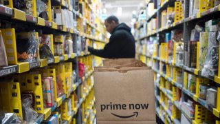 In this Wednesday, Dec. 20, 2017, file photo, a clerk reaches to a shelf to pick an item for a customer order at the Amazon Prime warehouse, in New York.