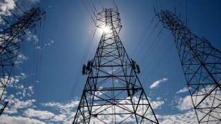 The sun shines over towers carrying electical lines.