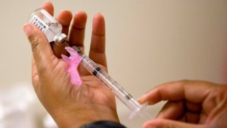 Flu vaccine being drawn from a vial into a syringe.