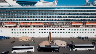 Passengers getting off cruise ship and onto buses.