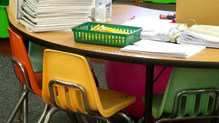 Chairs around a table with papers on it inside a school.