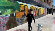 A woman takes a picture of a mural honoring George Floyd in downtown Oakland.